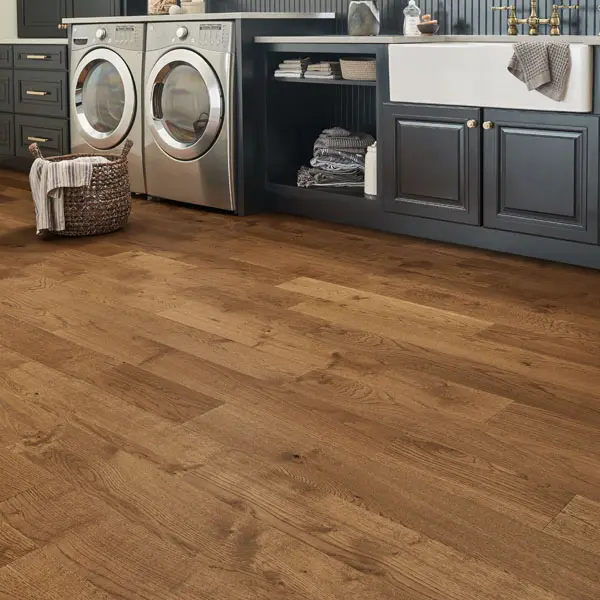 craft brown Entryway scene - Boots and shoes by door, small rug in front of door, purse sitting on chest of drawers, laminate flooring.